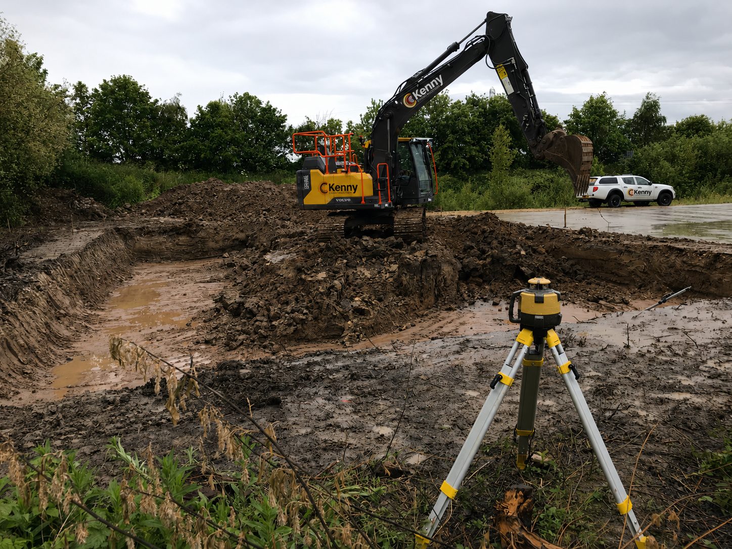 PT Kenny Construction excavator on a foundation excavation with a laser level set up in the foreground