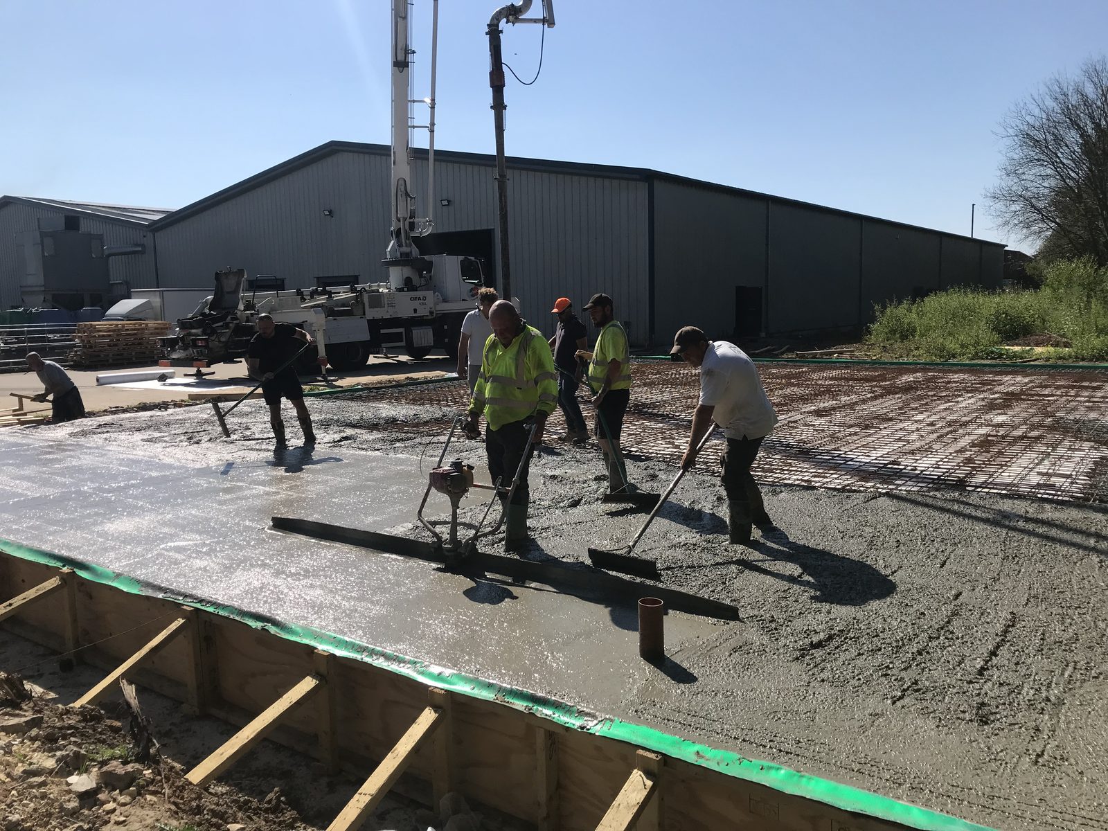 Site team spreading and screeding concrete during a slab pour