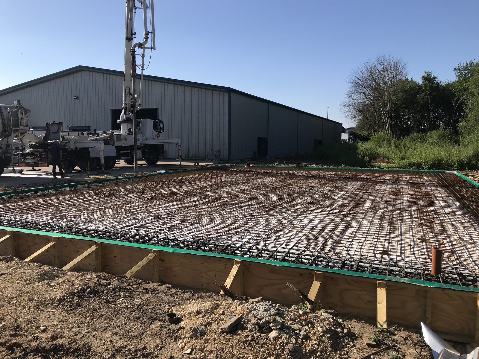 Reinforcement mesh ready for a concrete pour with a concrete pump behind